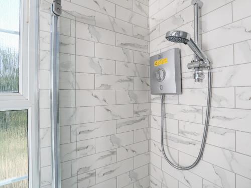 a shower in a bathroom with white tiles at Ferrystone in Dartmouth