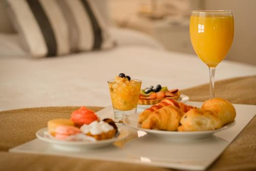 a tray with two plates of food and a glass of orange juice at Hotel Carat Apart Boutique in Rosario