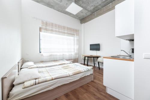 a white bedroom with a bed and a kitchen at LKS Apartment 5 in Tallinn