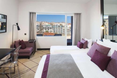 a hotel room with two beds and a window at Avani Avenida Liberdade Lisbon Hotel in Lisbon
