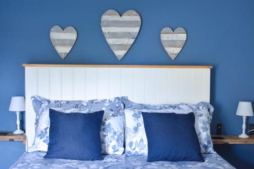 a blue bedroom with a bed with two hearts on the wall at Seagull Cottage - Suffolk Coastal Escapes in Pakefield