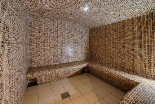 La salle de bains est pourvue de murs carrelés et d'une baignoire. dans l'établissement NH Lyon Airport, à Saint-Exupéry