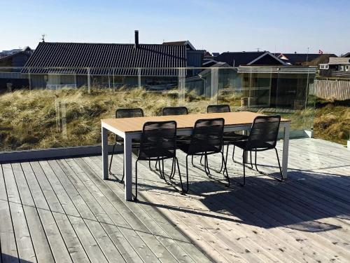 une table en bois avec quatre chaises sur une terrasse dans l'établissement 9 person holiday home in Thisted, à Nørre Vorupør