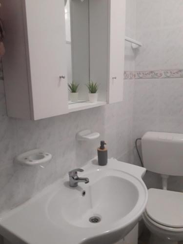Un baño con un lavabo blanco y un inodoro. en Aconchego Alojamento Local, en Nazaré