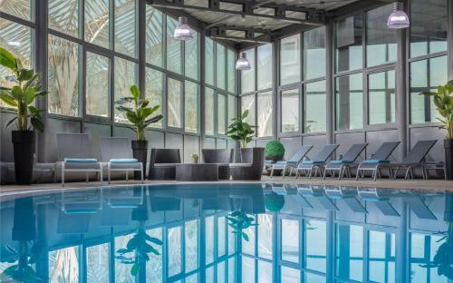 a pool in a building with chairs and windows at Tivoli Oriente Lisboa Hotel in Lisbon