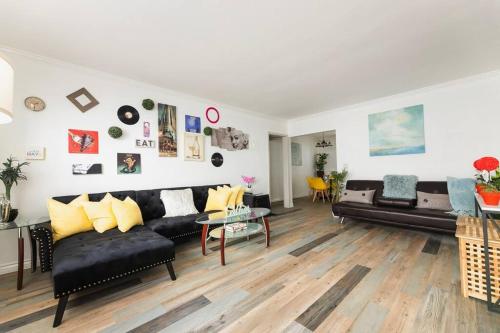 a living room with black couches and yellow pillows at Charming LA 2 Bedroom For Your Home Away From Home in Los Angeles
