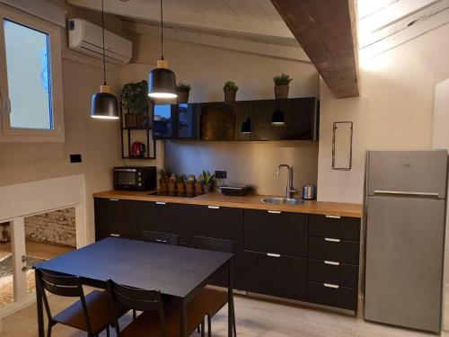 Il comprend une cuisine équipée d'une table et d'un réfrigérateur. dans l'établissement La Perla del Centro, à Bologne