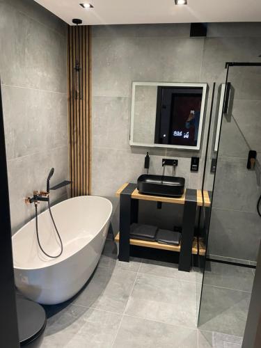 a bathroom with a tub and a tv on the wall at Apartament Grey Love w Czeladzi, FV, 8km do Katowic in Czeladź