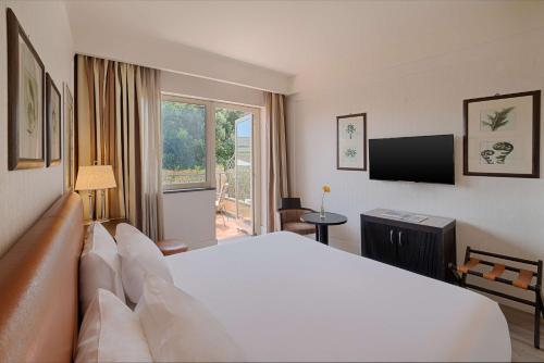 a hotel room with a bed and a television at NH Catania Parco degli Aragonesi in Catania