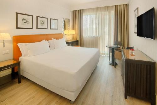 a large white bed in a hotel room at NH Catania Parco degli Aragonesi in Catania