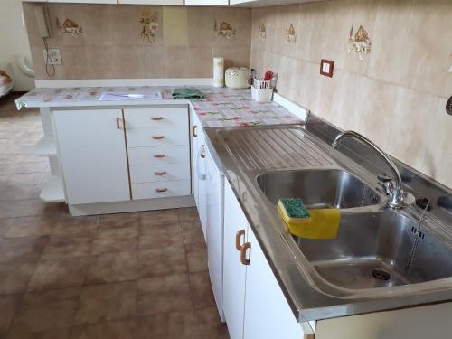a kitchen with a stainless steel sink and white cabinets at Villa Ambra in Vigolo