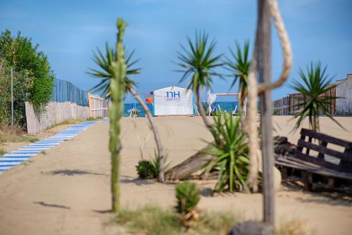 a beach with a bench and palm trees at NH Catania Parco degli Aragonesi in Catania