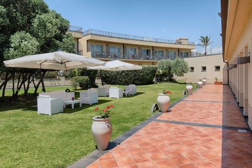 a patio with white umbrellas and tables and chairs at NH Catania Parco degli Aragonesi in Catania