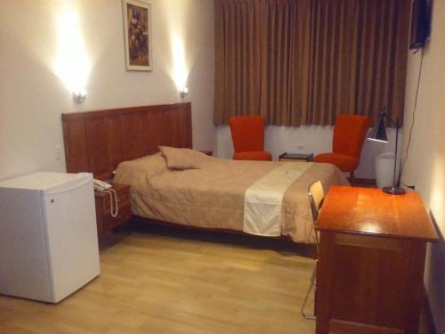 um quarto de hotel com uma cama e duas cadeiras laranja em SAFARI HOTEL IQUITOS em Iquitos