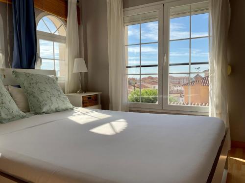 - une chambre avec un grand lit blanc et une fenêtre dans l'établissement At Home in Malaga Stay & Solo Travellers, à Rincón de la Victoria