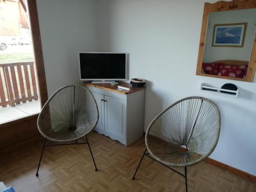 duas cadeiras sentadas numa sala de estar com televisão em Espace et confort dans station familiale à 1800 m em Puy-Saint-Vincent
