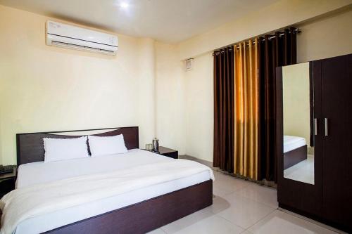 Un dormitorio con una gran cama blanca y una ventana en Hotel Sunshine, en Kāshīpur