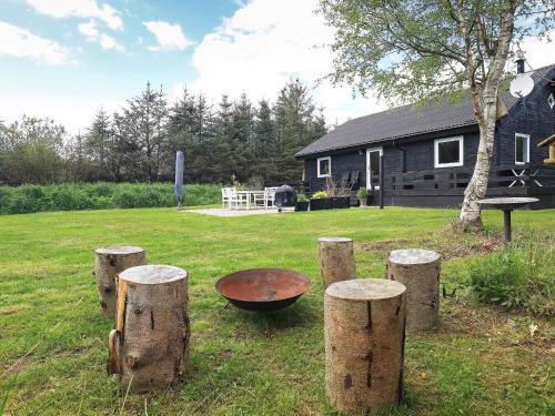 a group of logs in a yard with a grill at 6 person holiday home in Hals in Hals