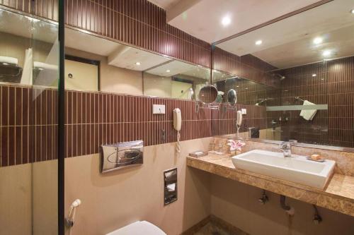 ein Badezimmer mit einem Waschbecken, einem WC und einem Spiegel in der Unterkunft Fortune Park Panchwati, Kolkata - Member ITC's Hotel Group in Kalkutta