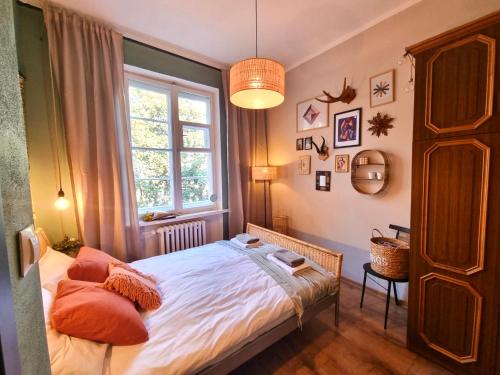 um quarto com uma cama com almofadas laranja e uma janela em Cozy&Retro - Old Town Apartament em Gdansk