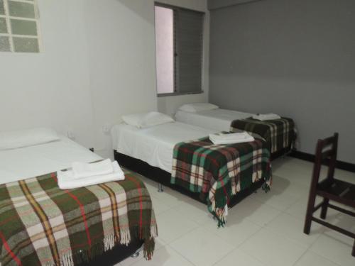 a hotel room with two beds and a chair at Hotel Economy 888 - By UP Hotel - Próximo a Praça da Estação e Rodoviária in Belo Horizonte