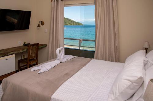 a bedroom with a bed with a view of the ocean at La Coquille in Praia de Araçatiba