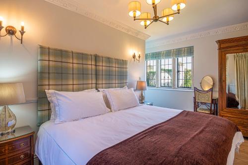 Un dormitorio con una gran cama blanca y una lámpara de araña. en Eagles Nest at Greyfriars, en Winchelsea