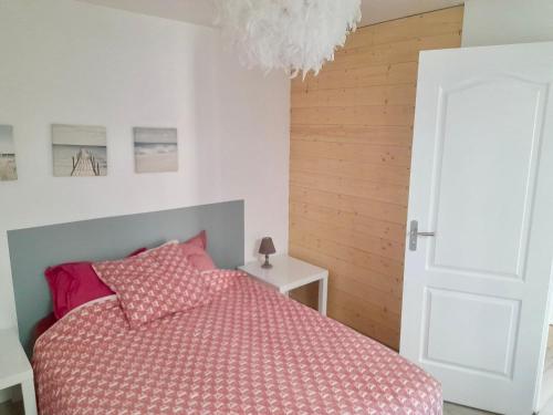Un dormitorio con una cama con sábanas rosas y una lámpara de araña. en Maisonnette Bassin d'Arcachon, en La Teste-de-Buch