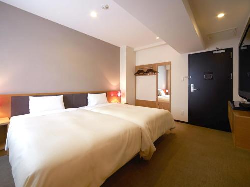 a large white bed in a room with a tv at Vessel Inn Hakata Nakasu in Fukuoka