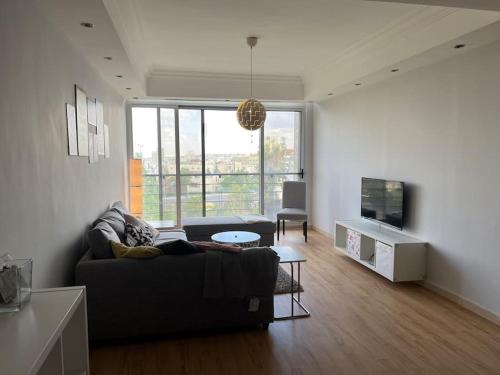 uma sala de estar com um sofá e uma televisão em Ronza Elegant Apartment em Amã