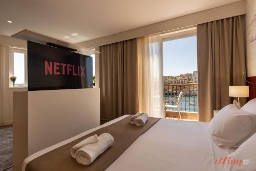 a hotel room with a television and towels on a bed at El Doris Boutique Living in Marsaskala