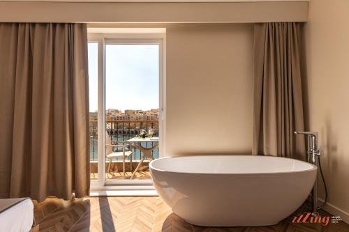 a large white bath tub in a room with a balcony at Eldoris Boutique Living in Marsaskala