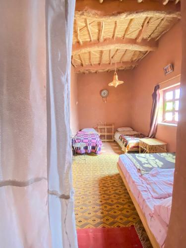 um quarto com duas camas e um tecto em auberge restau tombouctou em Aït Ben Haddou