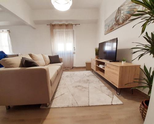 a living room with a couch and a flat screen tv at Aconchego Alojamento Local in Nazaré