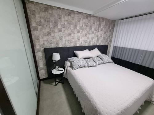 a bedroom with a white bed and a brick wall at Loft silgar in Sanxenxo