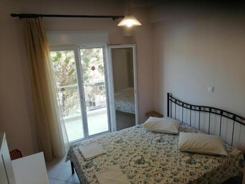 a bedroom with a bed and a large window at KALIPSO STUDIOS in Nikiti
