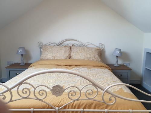 een bed in een slaapkamer met 2 lampen op tafels bij Bwthyn Mair in Llangefni