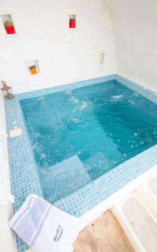 a large swimming pool with blue tiles in a room at The Anchor House in Symi