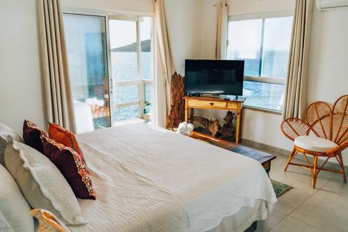 a bedroom with a bed and a tv and a window at Casa Grega in Arraial do Cabo