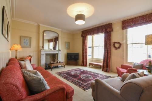a living room with red couches and a fireplace at Walton House, Southwold in Southwold
