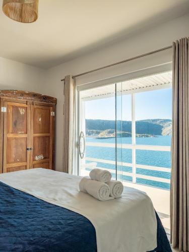 a bedroom with a bed and a large window at Casa Santorini Terrace in Arraial do Cabo