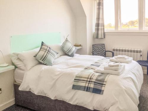 a bedroom with a large white bed with towels on it at Shoreline in Connel