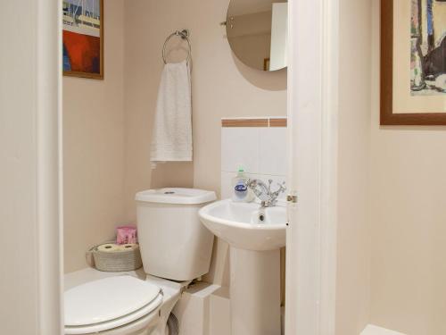 a white bathroom with a toilet and a sink at The Wee Hoose in Kinghorn