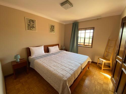 a bedroom with a bed and a chair and a window at Casa Riamar in São Jacinto