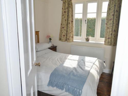 a bedroom with a bed and two windows at The Old W I Hall in Staunton in the Vale