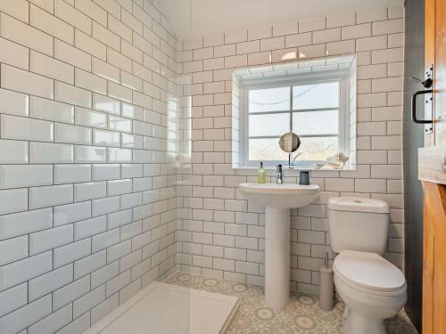 a white bathroom with a toilet and a sink at Keepers Cottage in Grimston
