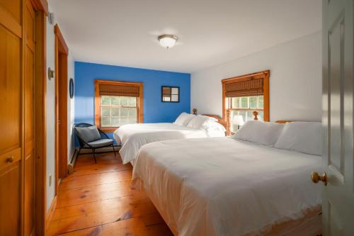 um quarto com 2 camas e uma parede azul em Colonial Home Directly on Kingdom Trails! em East Burke