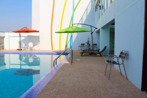 a swimming pool with chairs and umbrellas next to a building at 42C The Chic Hotel in Nakhon Sawan