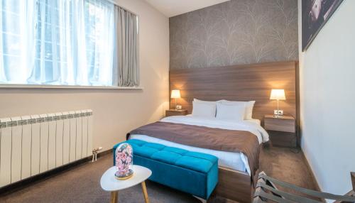 une chambre d'hôtel avec un lit et un canapé bleu dans l'établissement Veneti Suites, à Belgrade