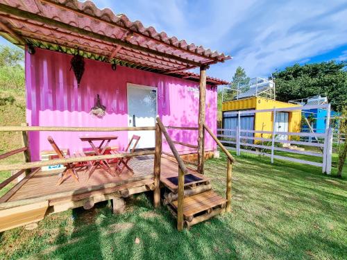 a pink house with a table and chairs on a deck at Pousada Recanto dos Bentos in Itapeva